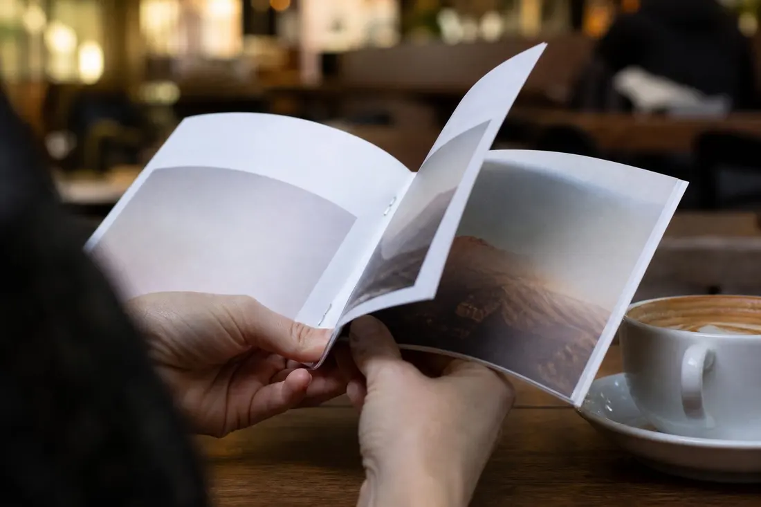 Hands leafing through a freshly printed booklet to check the proof